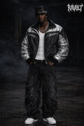 Homme portant un jean baggy noir RAVØLT avec motif flames, tenue streetwear techno et look oversized urbain